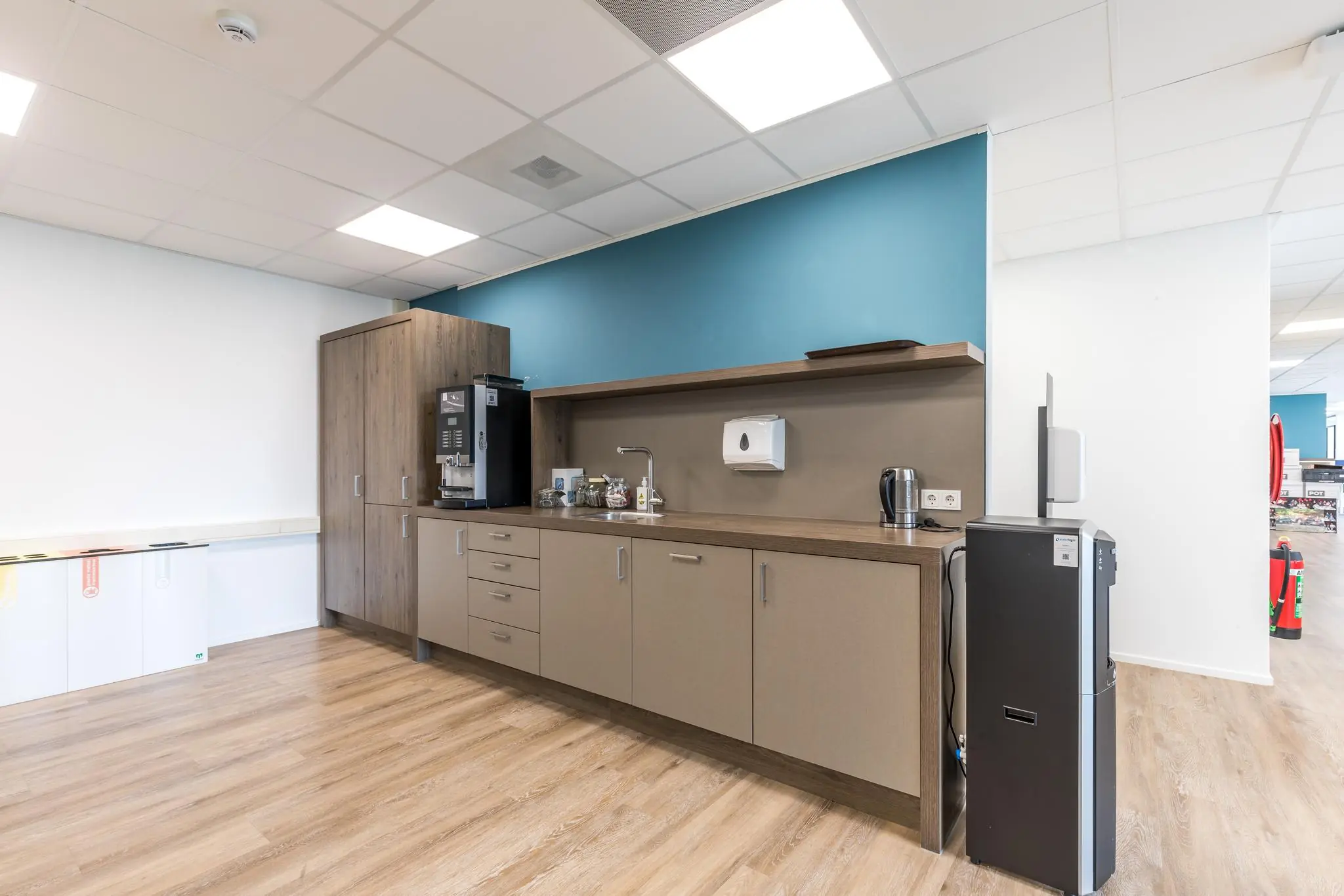 Moderne kitchenette in een kantoorruimte aan de Baarnsche Dijk met koffieautomaat, waterkoker en afvalscheidingsbakken.